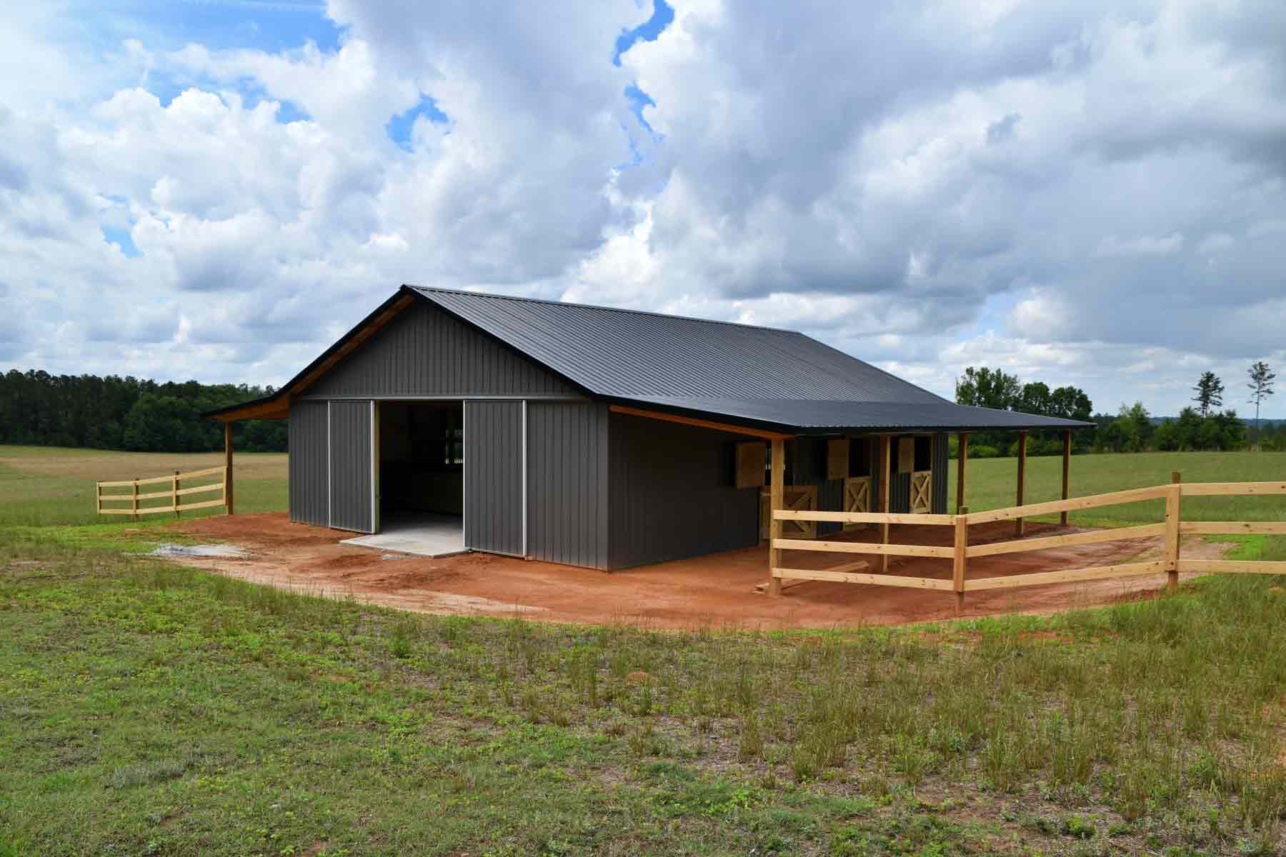 homeguide-horse-barn-with-six-stalls-sliding-doors-roof-overhang-split-rail-fence